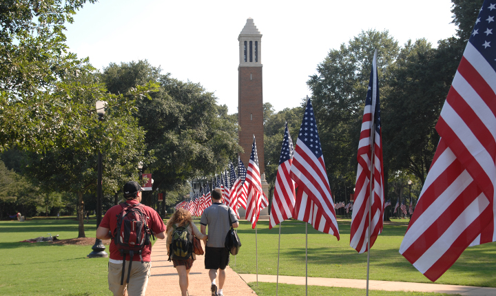 students walking by American flags on the Quad